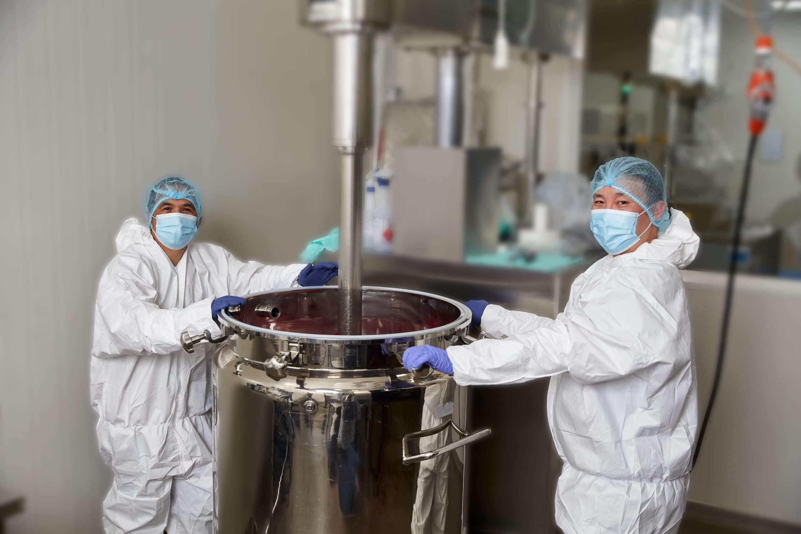 Two manufacturing production specialists using a mixer